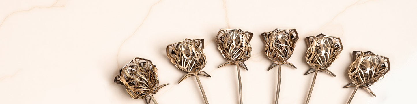 Collection of six bronze floral sculptures displayed in alignment on a soft cream marble surface