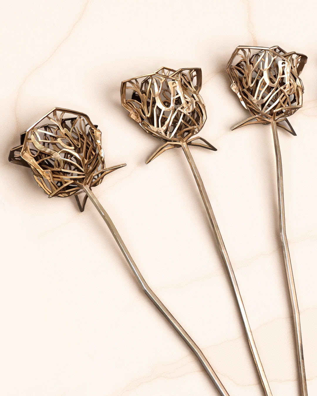 Collection of three bronze floral sculptures displayed in alignment on a soft cream marble surface